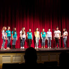 A group of 10 performers on stage.