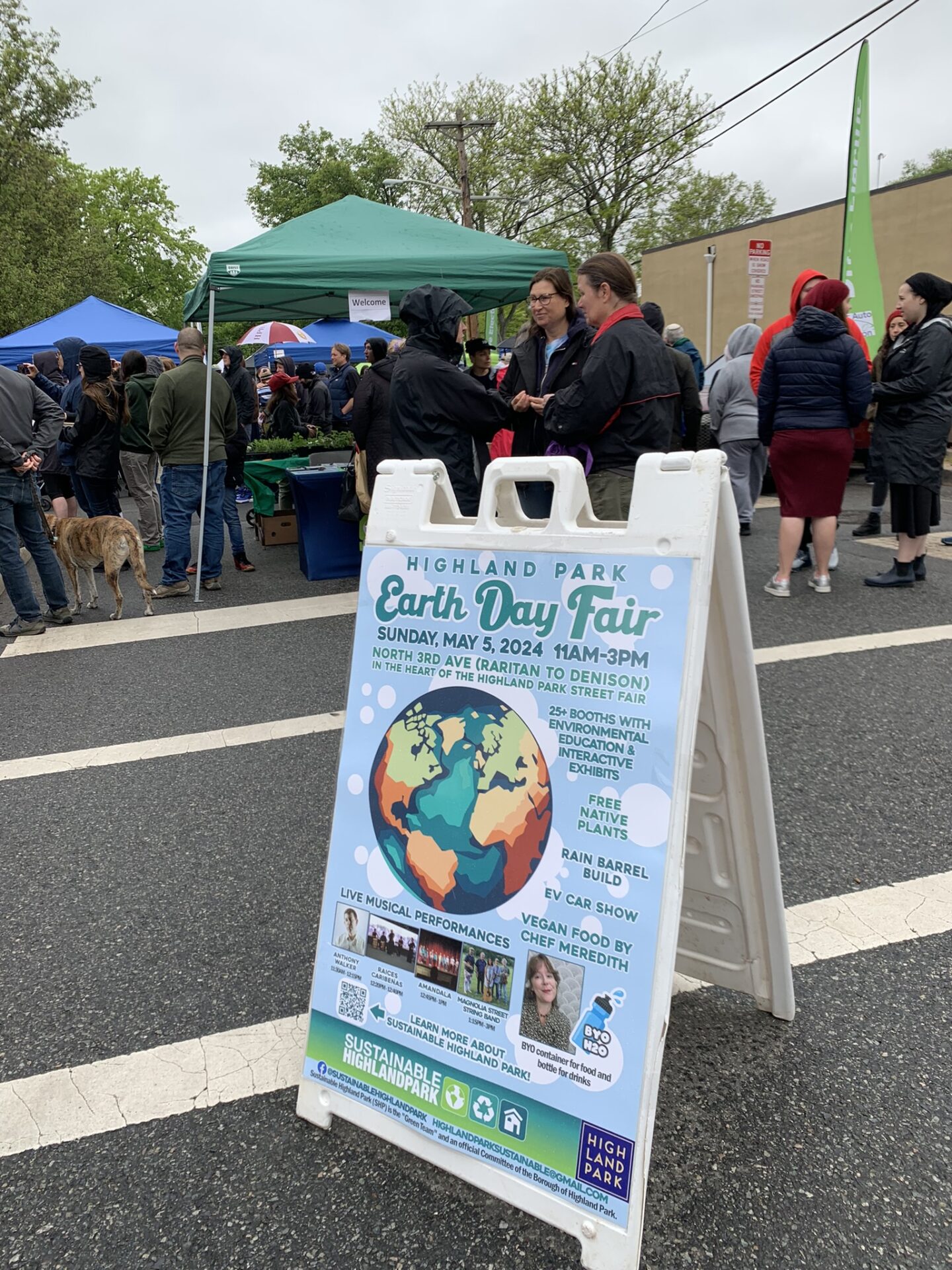 The crowd gathered around canopies and a sign for the Earth Day Fair.