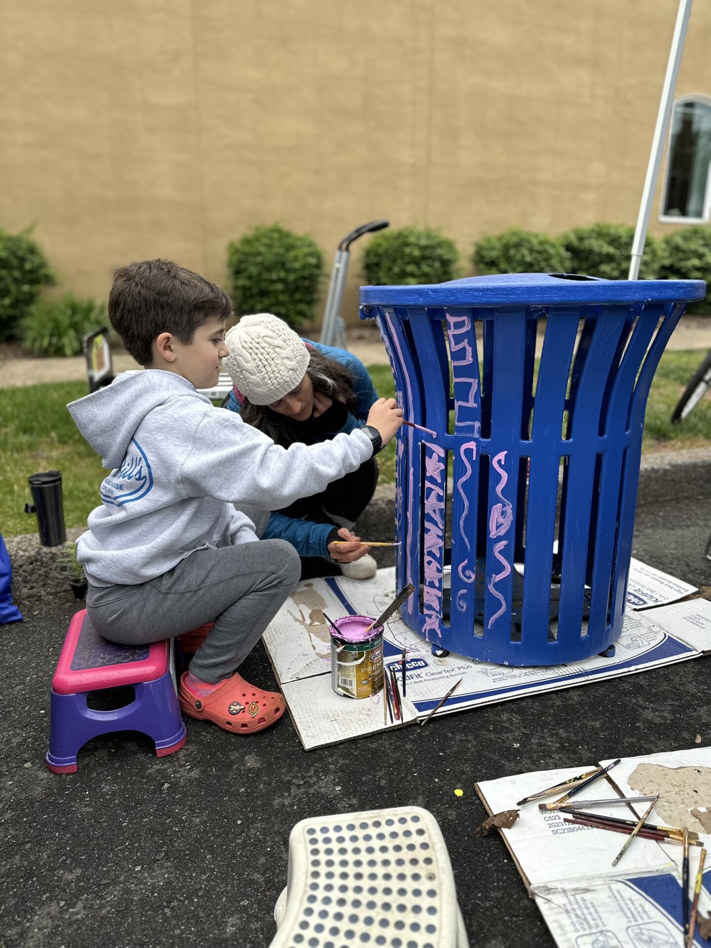 Kids painting a streetside trash bin.